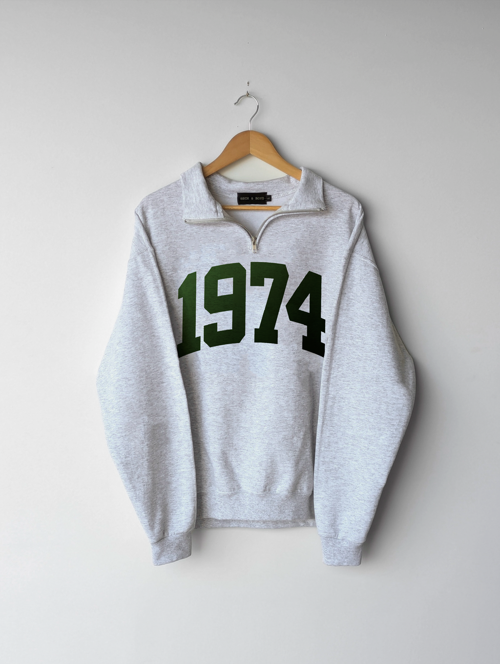 Gray quarter zip sweatshirt with '1974' printed on it, hanging on a wooden hanger against a white background. 1974, birthday, gift ideas