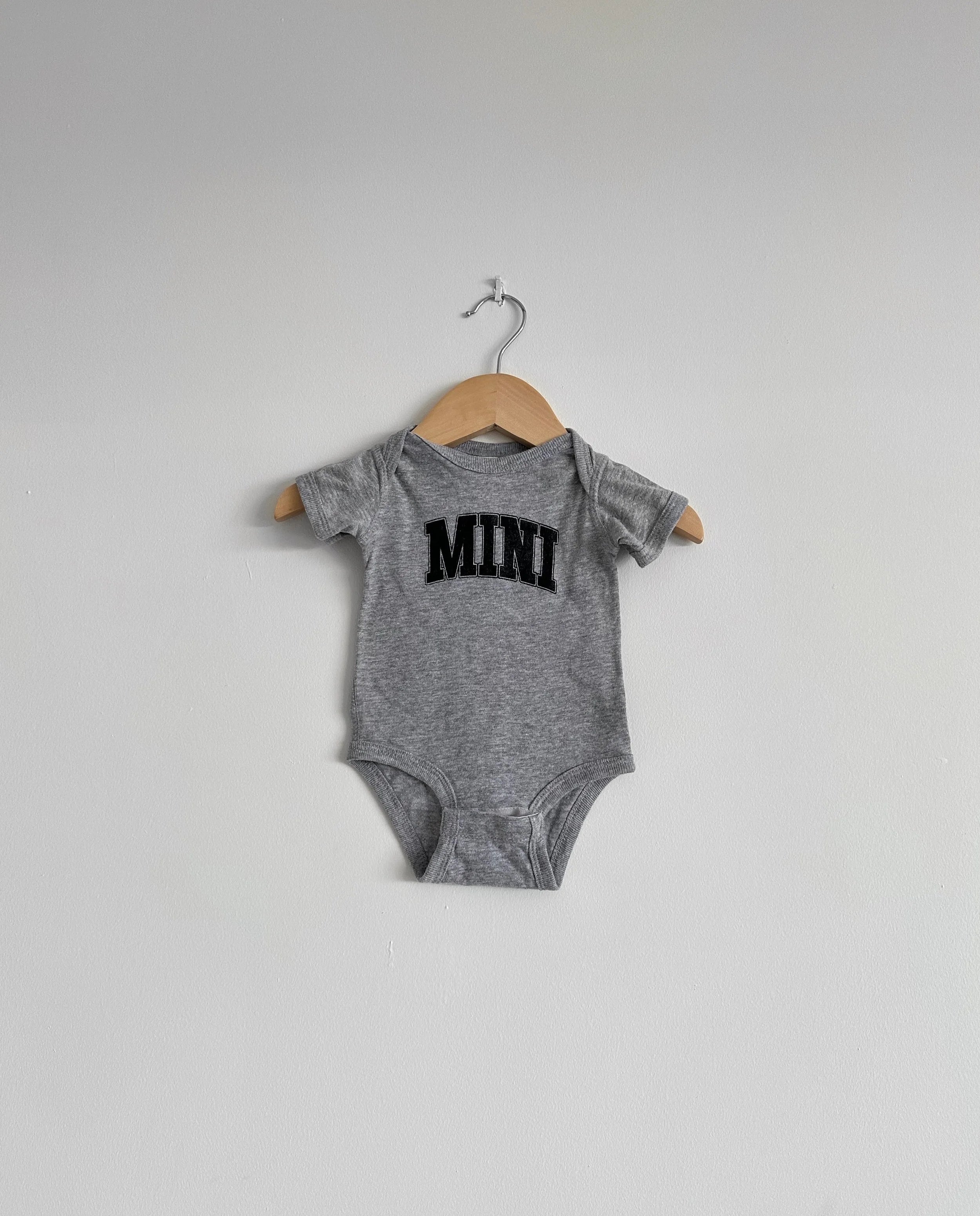 Grey baby onesie with 'MINI' print on a hanger against a white background, mini, matching, baby, baby jumper, onesie, cute