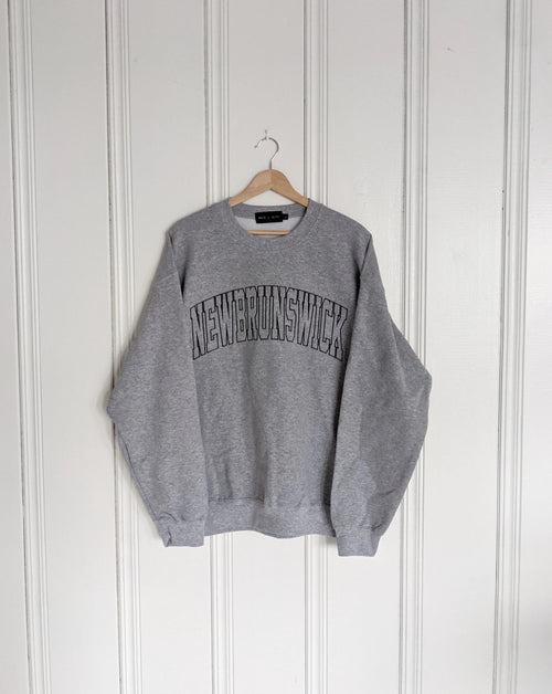 Grey sweatshirt with 'New Brunswick' text on a hanger against a white wall, Embroidered, Cozy, New Brunswick, NB, Maritimes, Gift Ideas