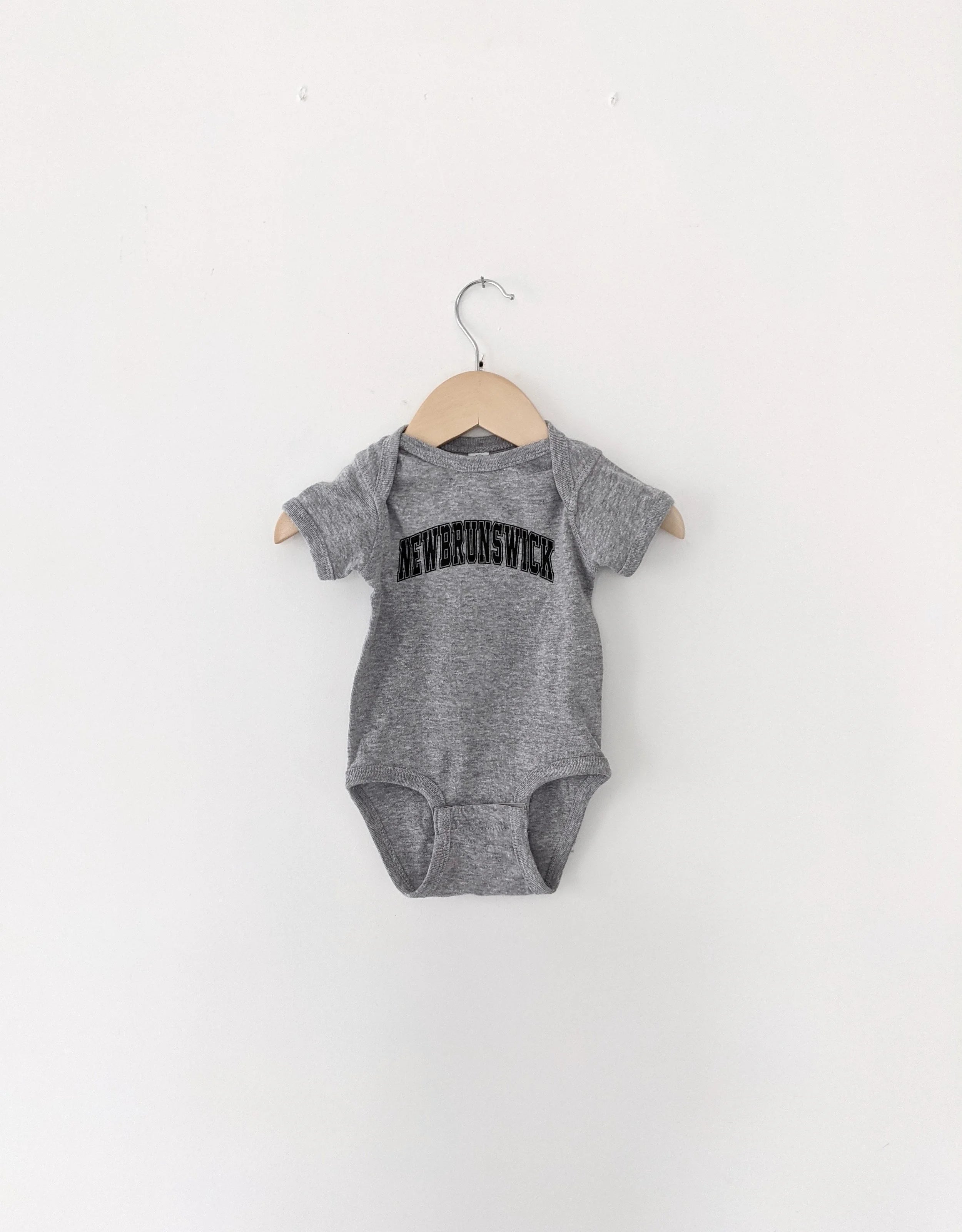 Grey baby onesie with 'Newborn' text on a white background, newborn, baby shower gift, new brunswick, baby jumper, jumper, cute