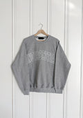 Grey sweatshirt with 'Nova Scotia' text on a hanger against a white paneled wall, Nova Scotia, Cozy, Maritimes, NS