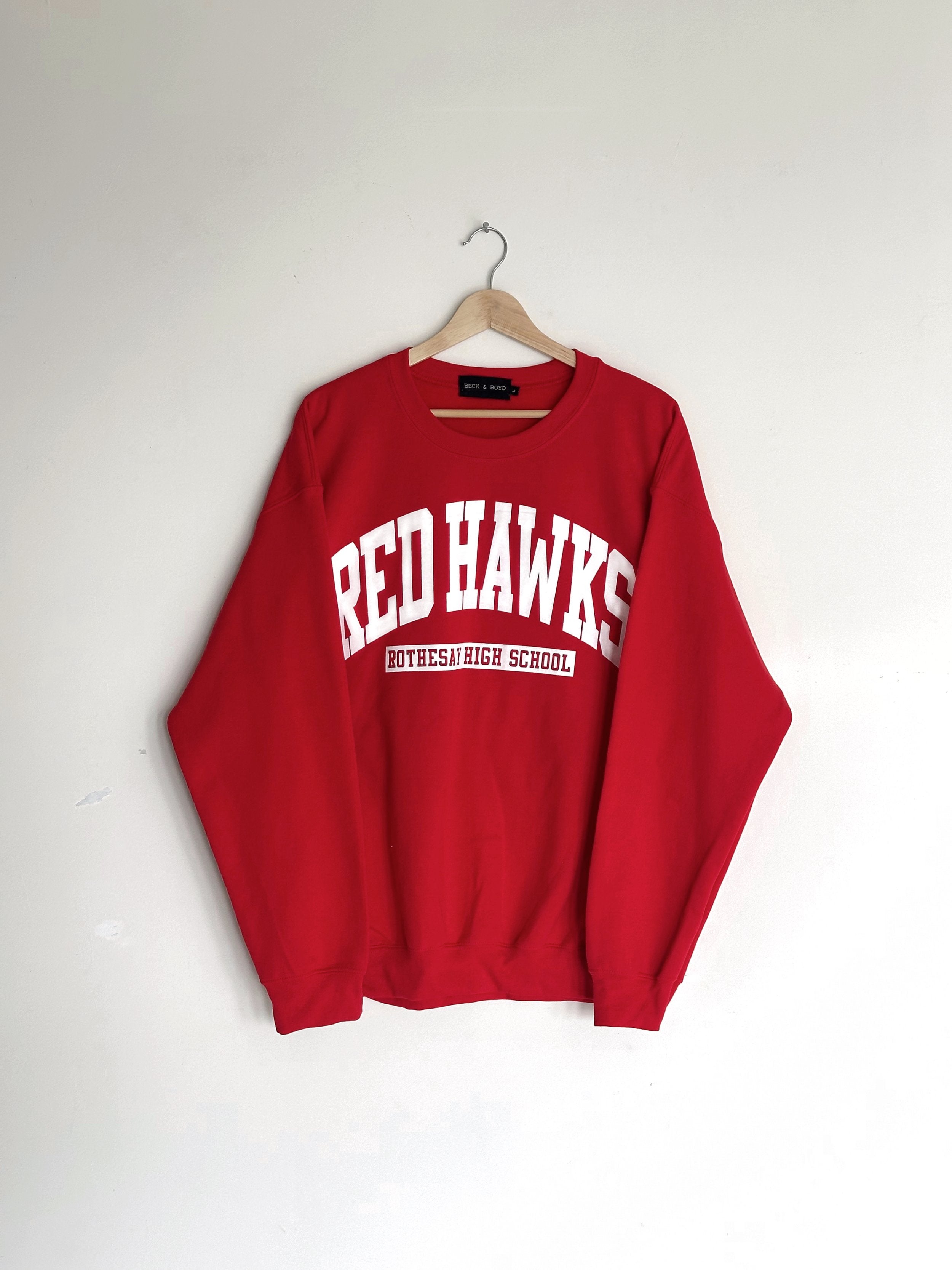 Red sweatshirt with 'RED HAWKS' text on a white background, Rothesay High School, Red Hawks, School merch
