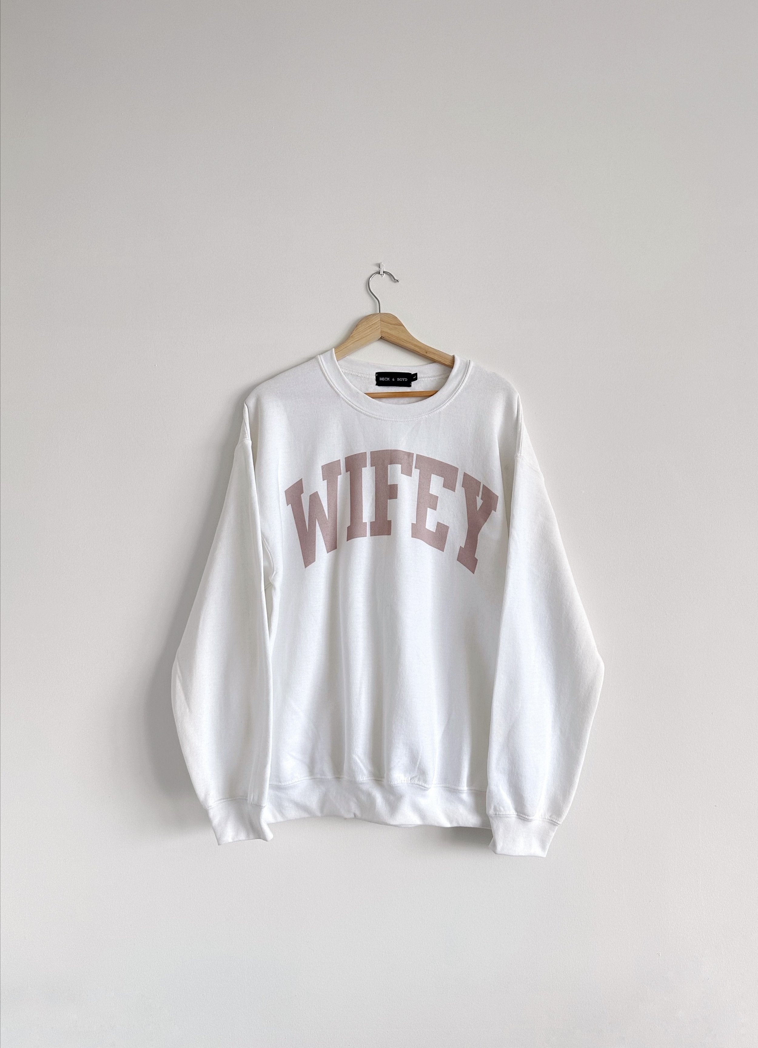 White sweatshirt with 'WIFEY' text on a hanger against a white background, newly wed, fiancee, wedding gift, wedding, cozy