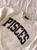 Beige sweatshirt with 'PISCES' printed in black on a white background, pisces, Birthday gift, zodiac, astrology, gift ideas, cozy